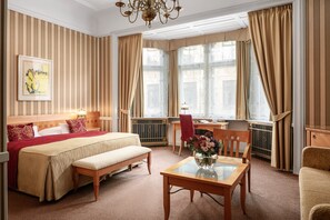 A hotel room with a large bed, a desk, a chair, and a small table with a vase of flowers. - Hotel Paris Prague (Prague)