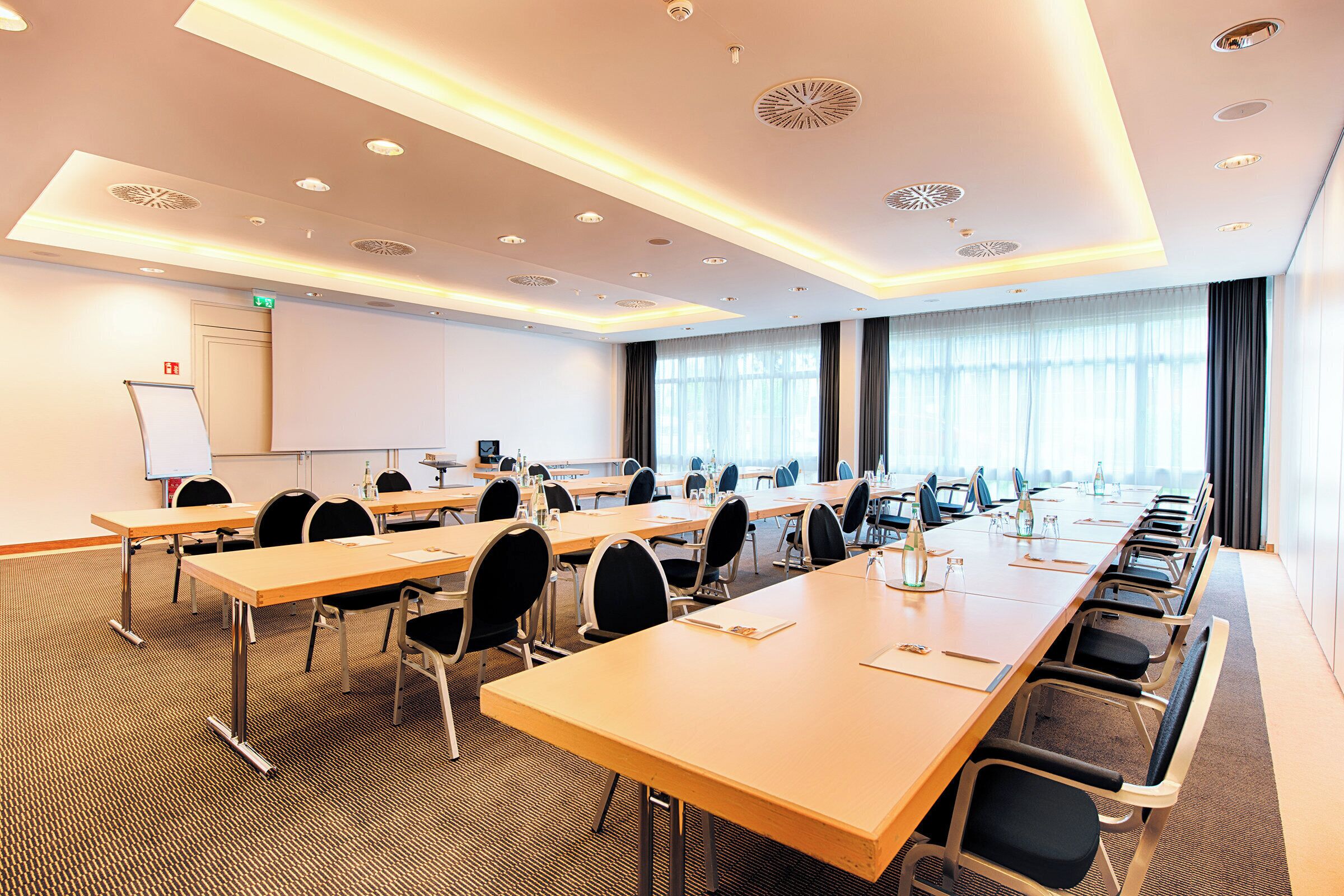 A conference room with multiple tables and chairs, a whiteboard, and a large window with curtains.