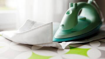 A green iron on a table with a white cloth.