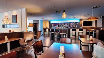 A modern bar area with wooden furniture, a bar counter, and a television screen.