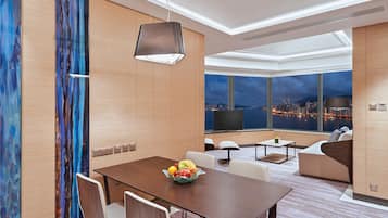 Une chambre d’hôtel moderne dotée d’un coin repas, d’un canapé et d’une grande fenêtre offrant une vue sur la ville.