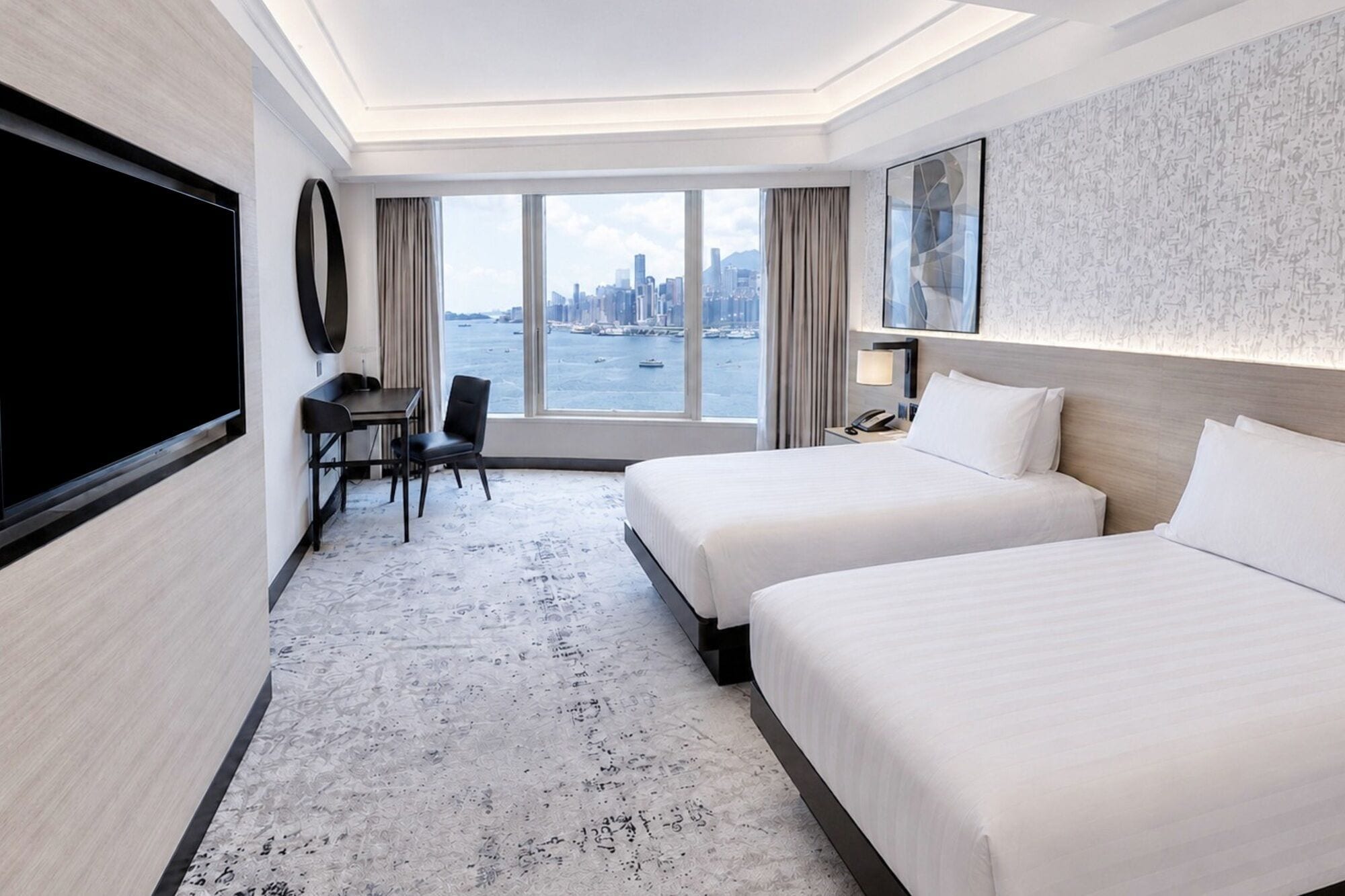 A hotel room with two beds, a desk, a chair, a TV, and a large window with a city view.