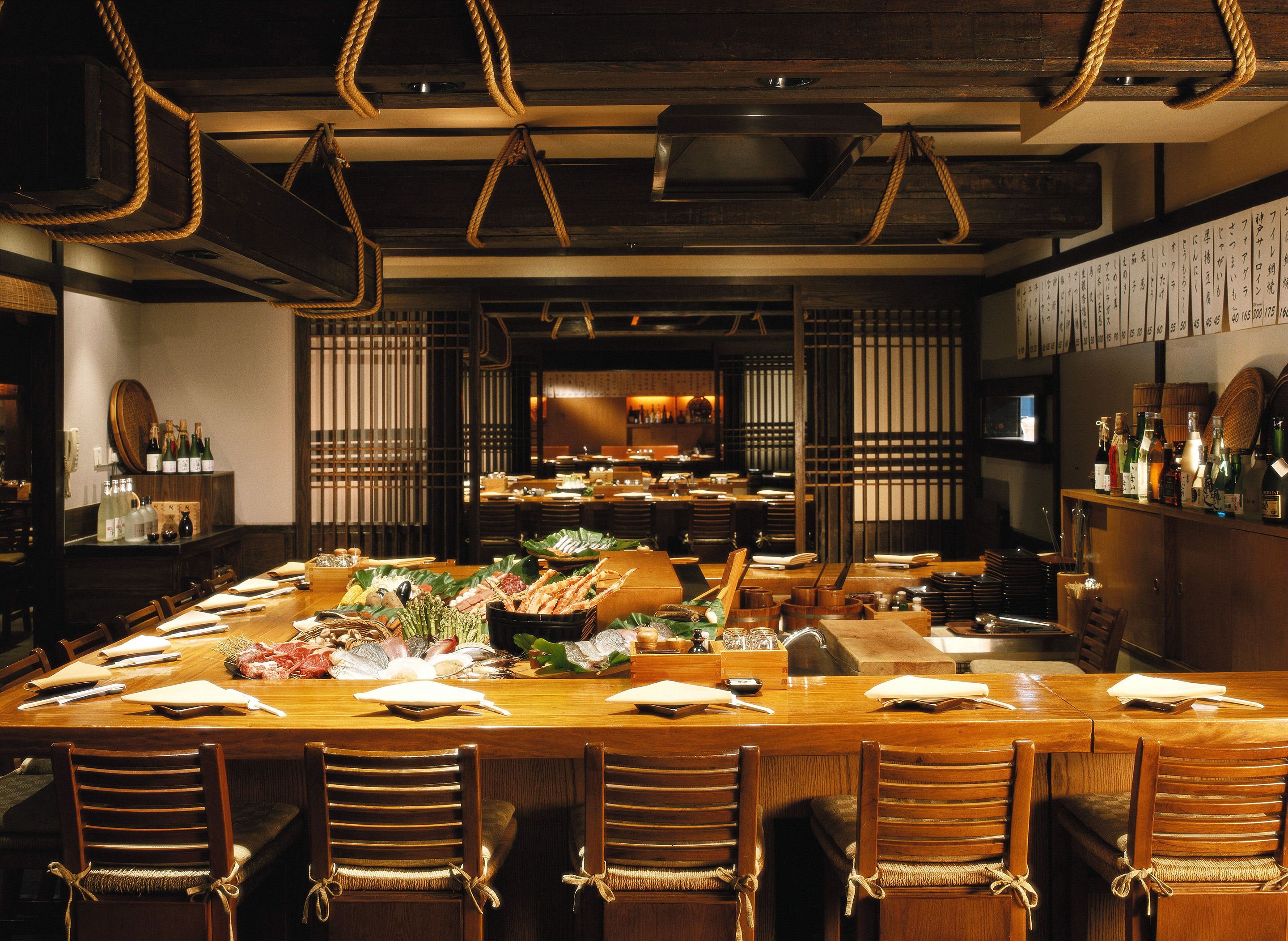 A restaurant with a long wooden table set for a meal, surrounded by wooden chairs.