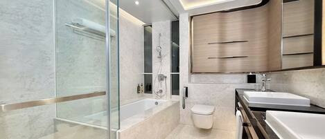 A modern bathroom with a glass-enclosed shower, a freestanding bathtub, a toilet, and a vanity with two sinks.