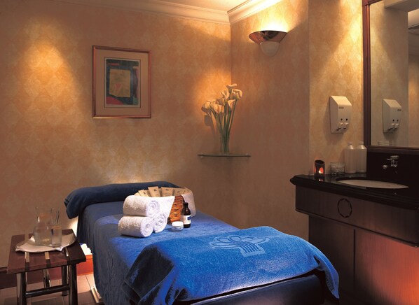 Une chambre d’hôtel avec un lit, une table de chevet, un miroir, un lavabo et un vase avec des fleurs.