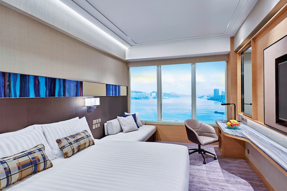 A hotel room with a large bed, a desk, a chair, and a TV.