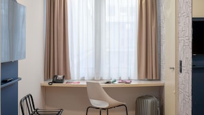 A hotel room with a desk, chair, bed, and a suitcase. - ibis Nürnberg Hauptbahnhof (Nuremberg)