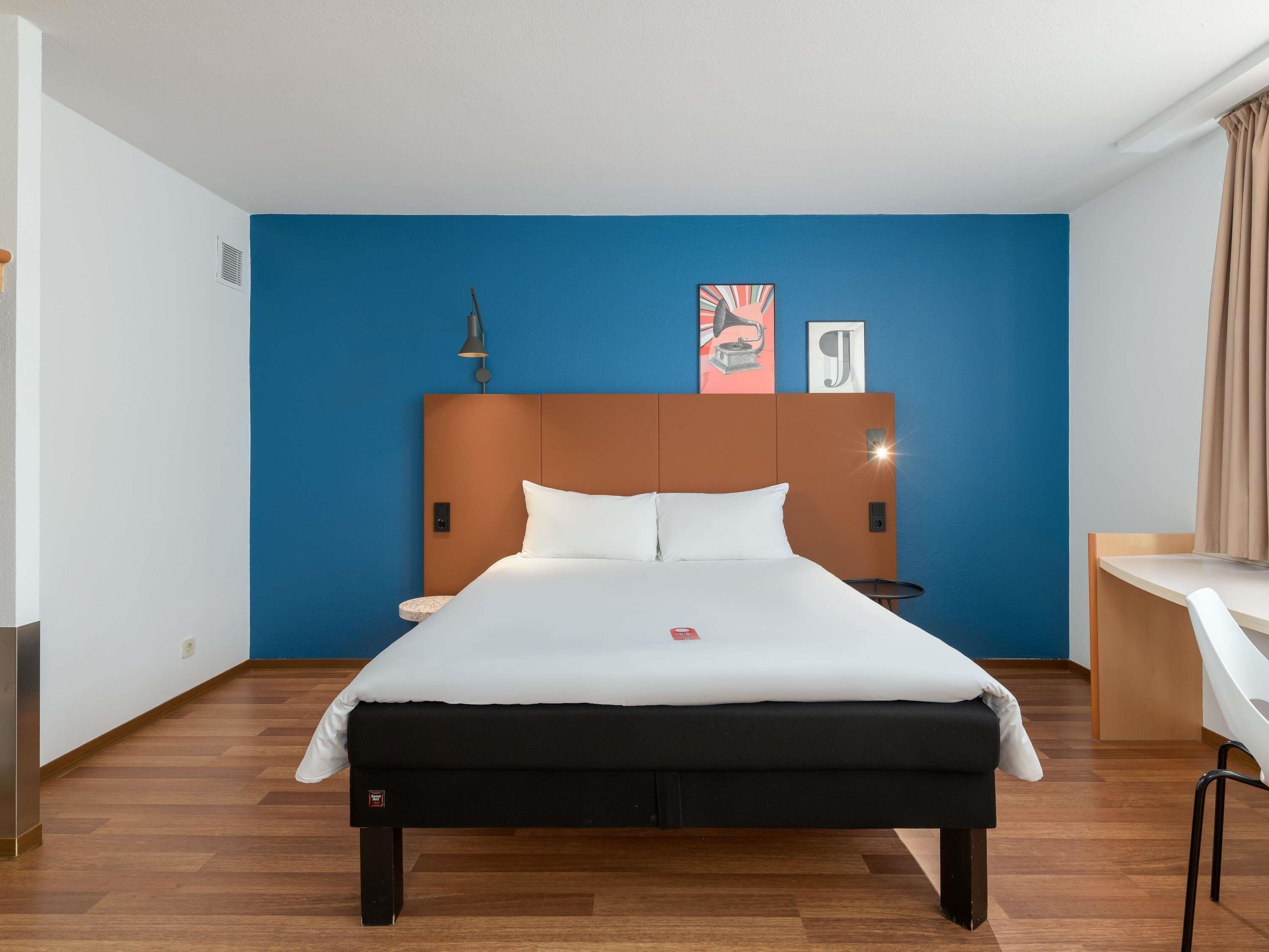 A hotel room with a bed, a desk, and a chair.
