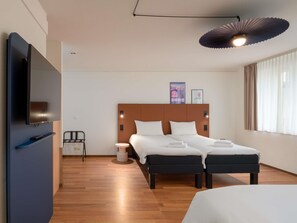 Een hotelkamer met een bed, nachtkastjes, een televisie en een plafondlamp.