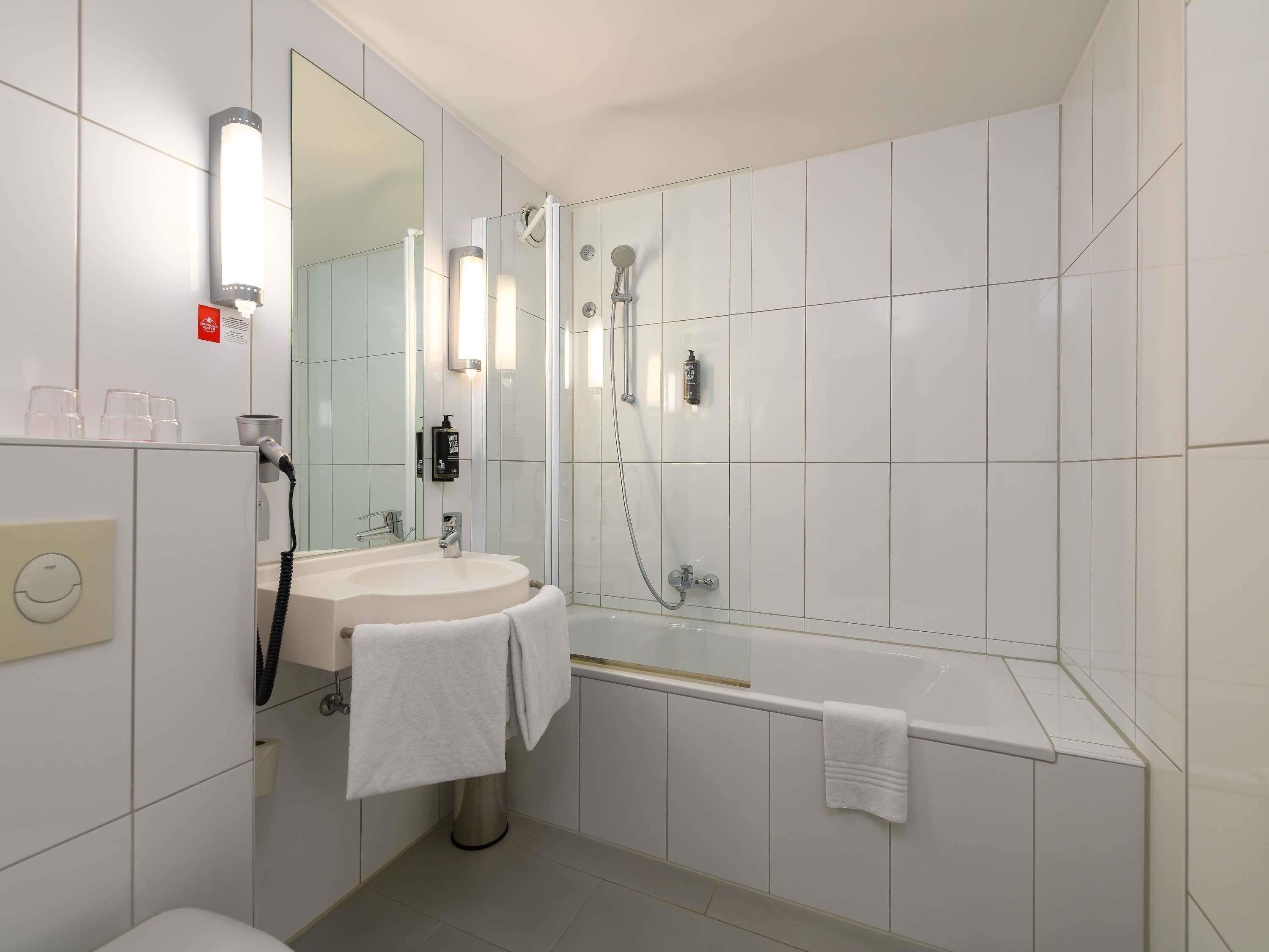 Une salle de bain moderne avec un lavabo blanc, un miroir et une douche.