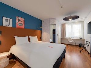 Habitación de hotel con una cama grande, un escritorio y una silla.