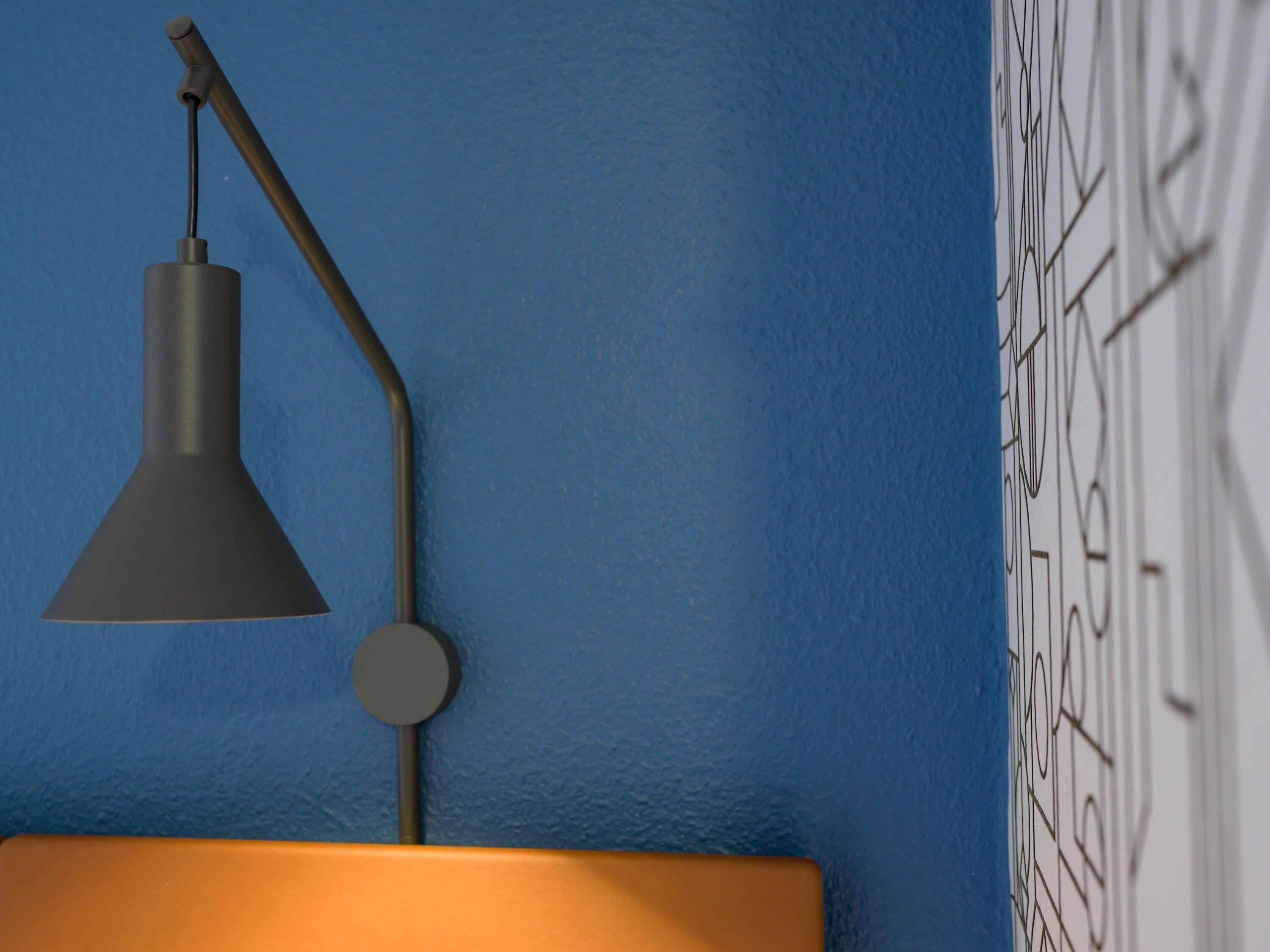 A lamp with a conical shade and a circular base on a wall.