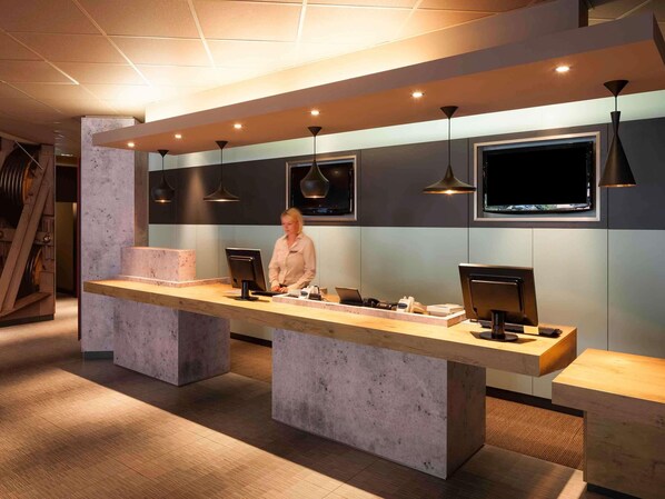 A reception desk with a modern design, a large flat-screen TV, and pendant lighting.