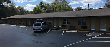 A motel with a parking lot, a van, and a row of rooms with windows.