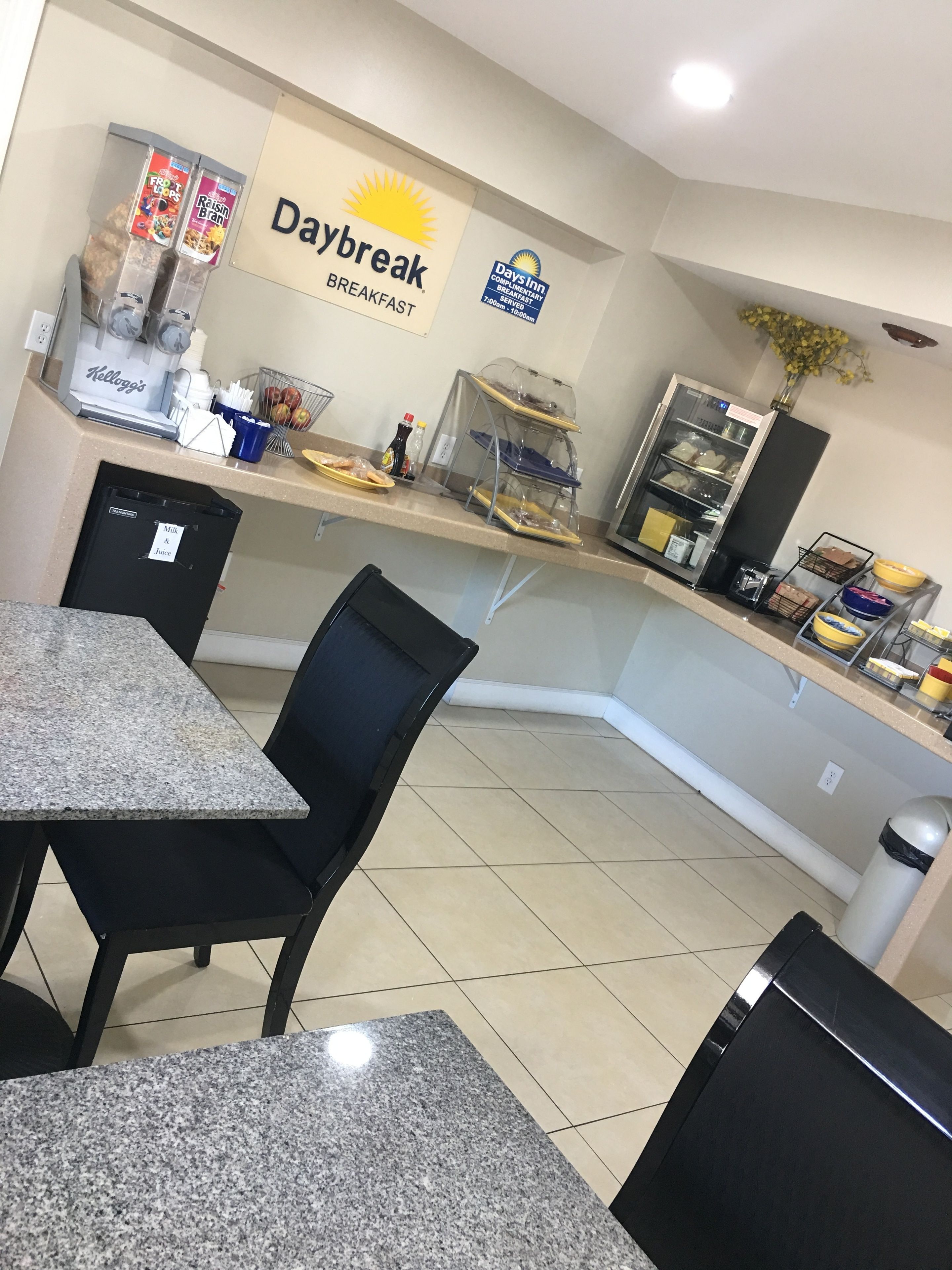 A breakfast area with a sign for Daybreak, a coffee machine, and a milk & juice cooler.
