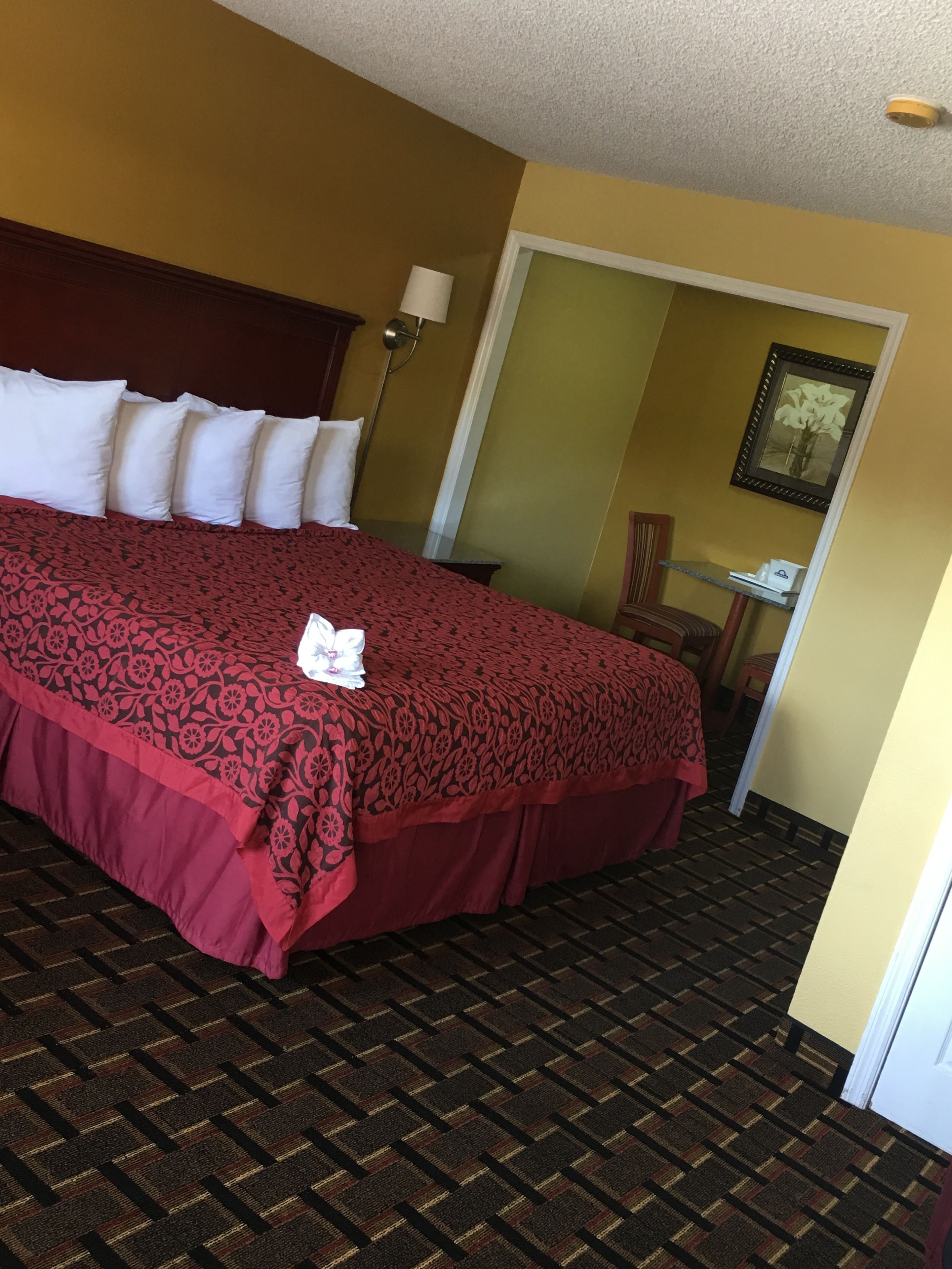 A hotel room with a large bed, a nightstand, a lamp, and a framed picture on the wall.