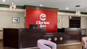Un comptoir d’accueil avec un logo rouge, une enseigne indiquant un restaurant et un salon, et une chaise à carreaux au premier plan.