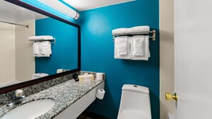 A bathroom with a blue wall, white sink, and toilet. There are towels hanging on a rack and a mirror above the sink. - Falls Church Inn (Falls Church)