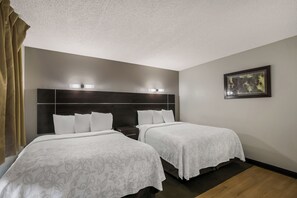 Habitación de hotel con dos camas, un cabecero oscuro y un cuadro en la pared.
