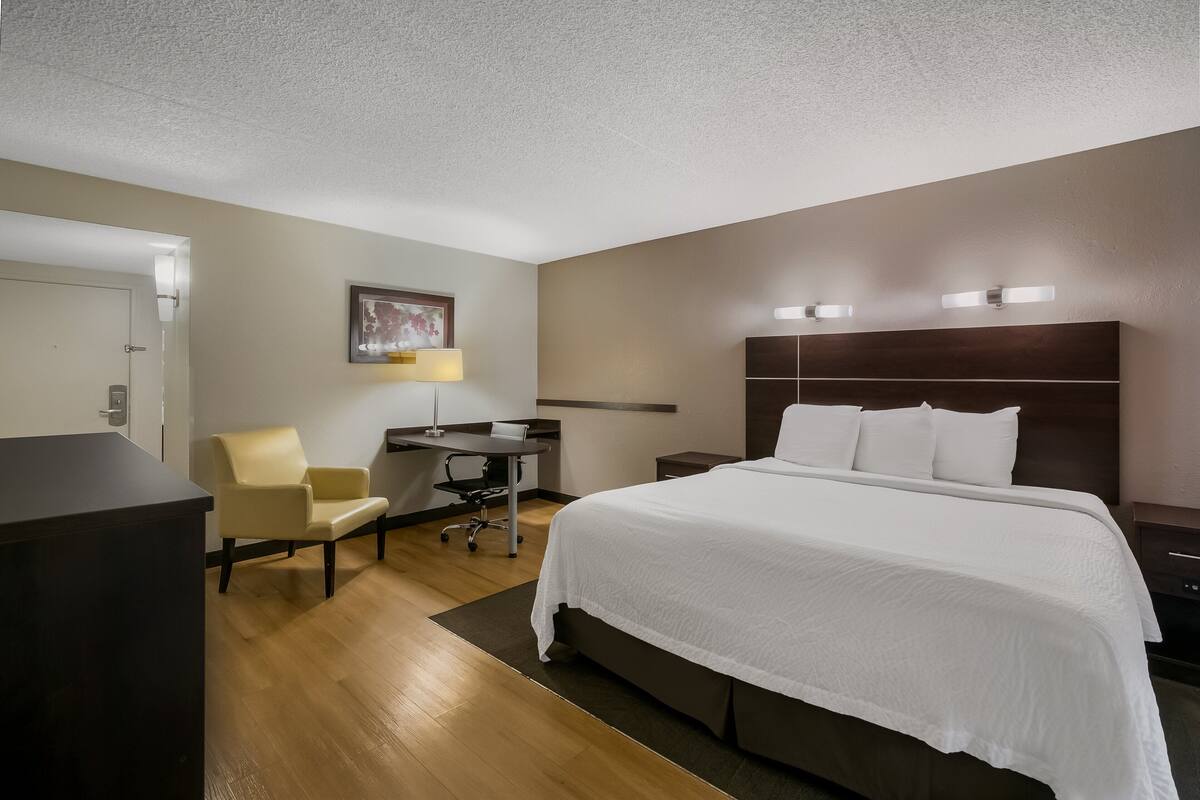 Ein Hotelzimmer mit einem großen Bett, einem Schreibtisch, einem Stuhl und einer Schreibtischlampe.