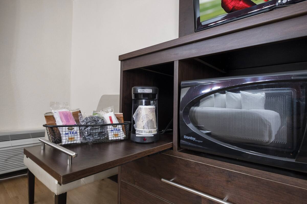 Eine Mikrowelle und eine Kaffeemaschine auf einer Holzauskładung in einem Hotelzimmer.