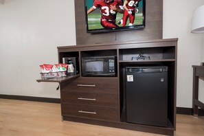 Una kitchenette equipada con microondas, refrigerador y televisor montado arriba.