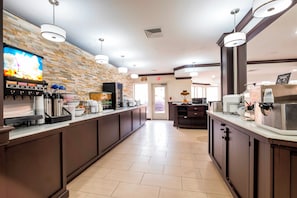 A modern kitchen area with a coffee machine, a microwave, and a display of baked goods. - Red Roof Inn PLUS+ & Suites Knoxville West-Cedar Bluff (Knoxville)