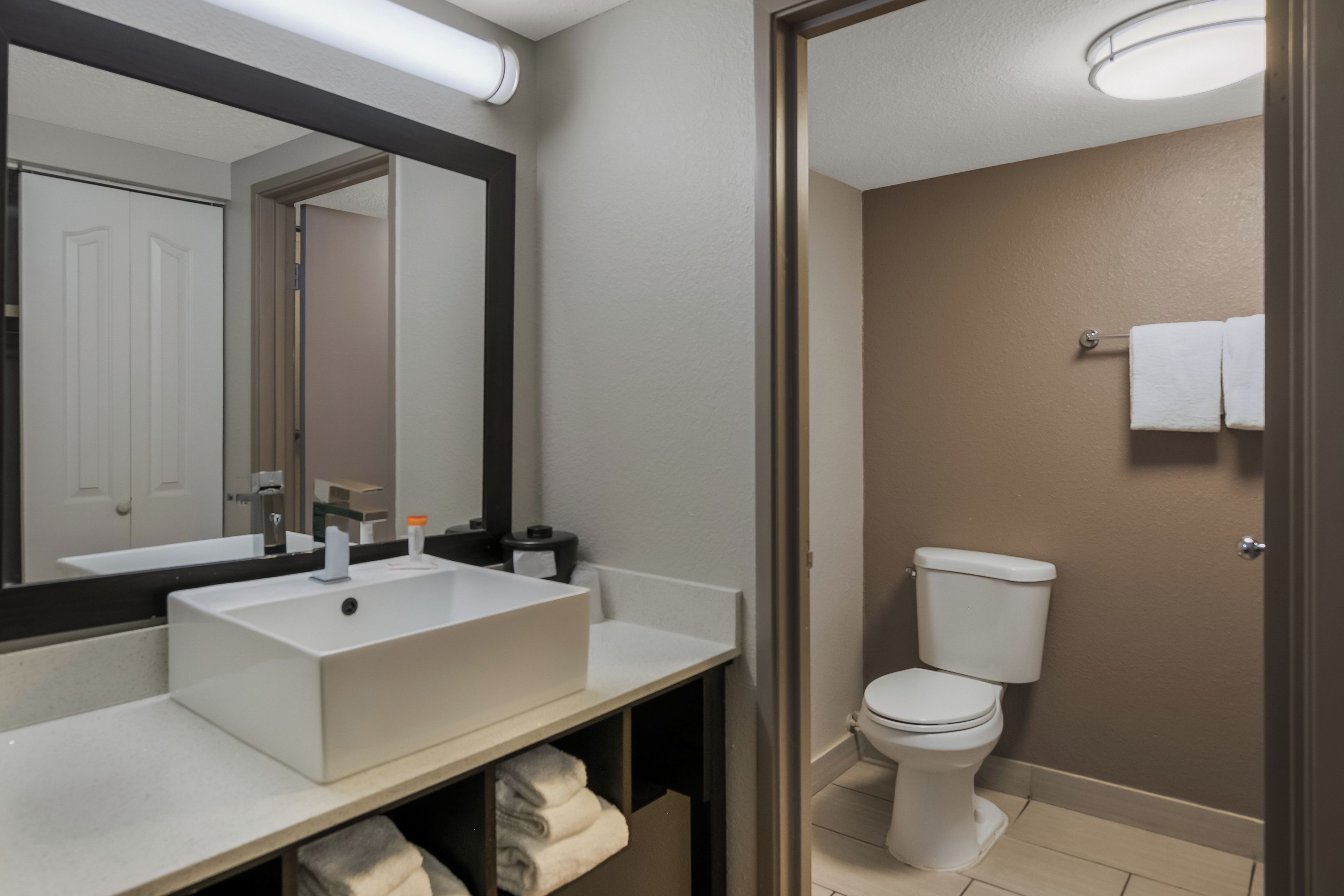 A bathroom with a white sink, a mirror, a toilet, and a towel rack.