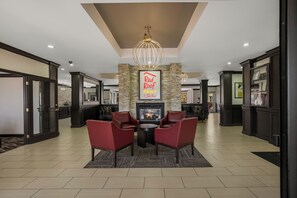 A spacious lobby with a fireplace, red leather chairs, and a Red Roof sign. - Red Roof Inn PLUS+ & Suites Knoxville West-Cedar Bluff (Knoxville)