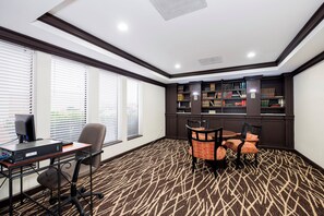 A conference room with a desk, chairs, a bookshelf, and a patterned carpet.