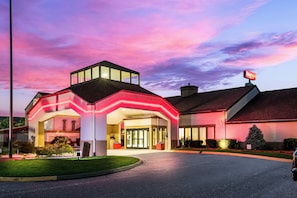 A hotel with a modern design, featuring a prominent entrance with a glass facade and a red neon sign above. - Red Roof Inn PLUS+ & Suites Knoxville West-Cedar Bluff (Knoxville)