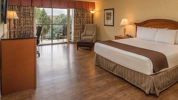 Habitación de hotel con una cama grande, un escritorio, una silla, una lámpara y vistas al exterior.