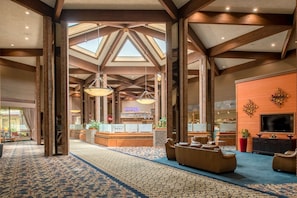 A spacious lobby with high ceilings, a reception desk, seating area, and a TV on the wall.