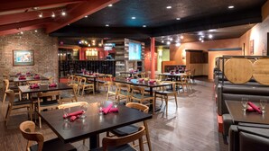 Un restaurante con varias mesas y cabinas, sillas de madera y una pared de ladrillo.