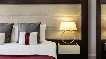 A hotel room with a large bed, a nightstand with a lamp, and a wooden headboard.