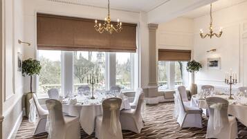 Un comedor formal con amplios ventanales, candelabros y una decoración en tonos blancos.