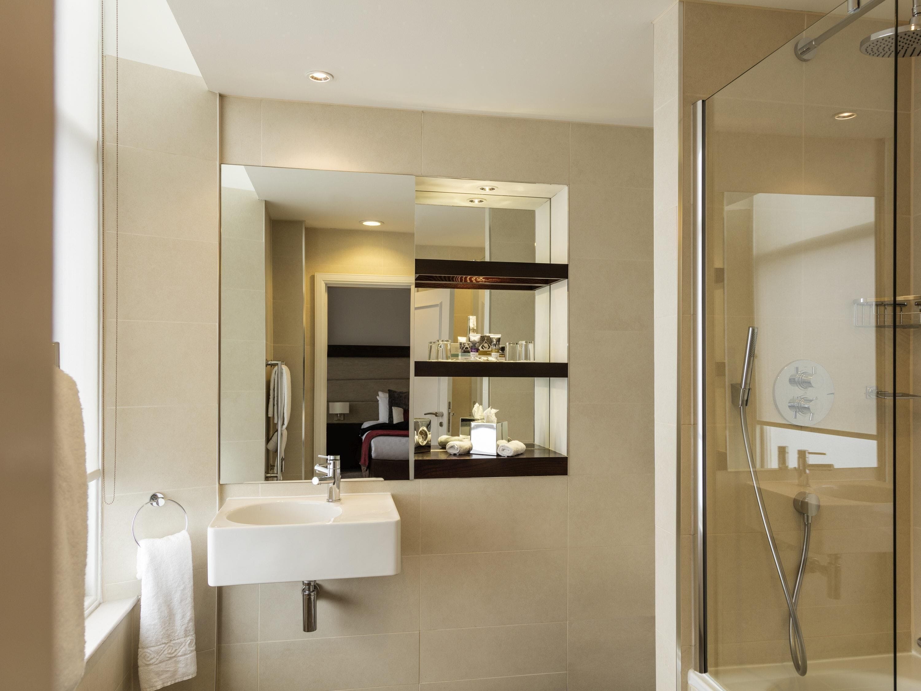 Un baño moderno con lavamanos, espejo y ducha.