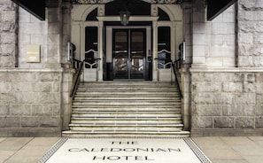 La entrada del Hotel Caledonian con escalones de piedra y un cartel en la parte inferior.