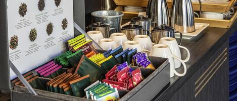 A tea station with a sign, tea bags, and tea pots.