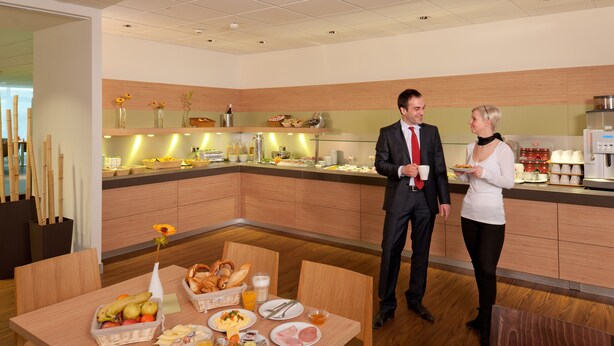 A breakfast buffet with various food items and a coffee machine. - ibis Augsburg Hauptbahnhof (Augsburg)