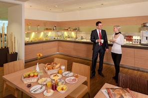 Ein Frühstücksbuffet mit verschiedenen Speisen und einer Kaffeemaschine.