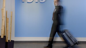 A man in a suit walking past a wall with the word 'ibis' and the phrase 'Augsburg beim Hauptbahnhof' on it. - ibis Augsburg Hauptbahnhof (Augsburg)
