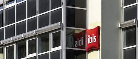 Fachada de edificio con múltiples ventanas y un letrero rojo que dice 'iobis'.