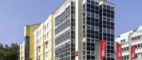 A multi-story hotel with a modern architectural design, featuring a prominent glass facade and multiple balconies.