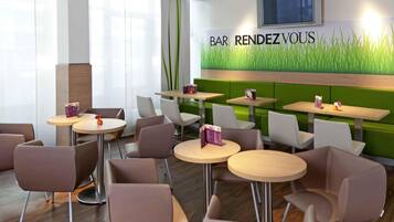 Ein modernes Restaurant mit grünen Sitzbänken, runden Tischen und einem an der Wand befestigten Fernseher.