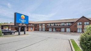 A Comfort Inn hotel with a large sign, a parking lot, and a building with multiple windows. - Comfort Inn Pickering (Pickering)