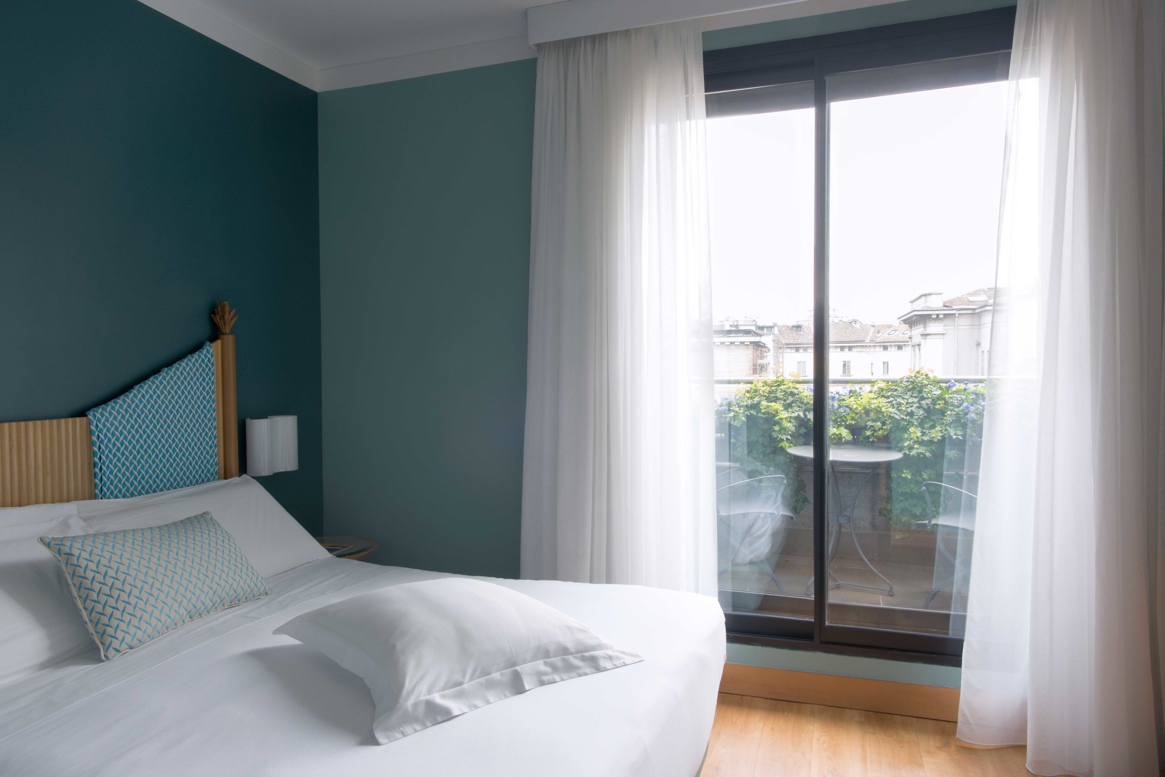 Una camera d'albergo con un letto, vista sull'esterno e una finestra con tende.