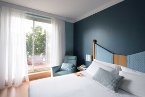 A hotel room with a large bed, a chair, a nightstand, and a view of the outdoors through a sliding door. - Hotel Spadari Al Duomo (Milan)
