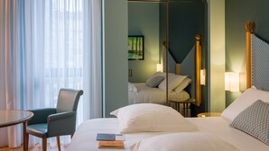 A hotel room with a bed, a chair, a table, and a large mirror. - Hotel Spadari Al Duomo (Milan)