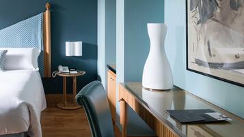 Een hotelkamer met een bed, een bureau, een stoel, een lamp en een schilderij aan de muur.